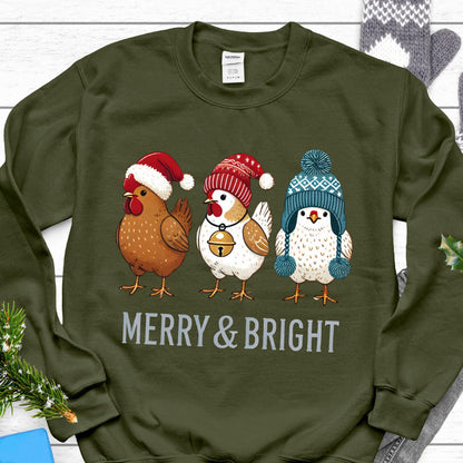 May include: A green sweatshirt with a Christmas-themed design featuring three chickens wearing festive hats. The chickens are wearing a red Santa hat, a red and white Santa hat, and a blue and white knit hat with a pom-pom. The text "Merry & Bright" is printed below the chickens.