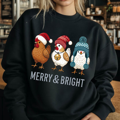 May include: Black sweatshirt with a festive design featuring three chickens wearing winter hats. The chickens are wearing a red and white Santa hat, a red and white stocking cap, and a blue and white knit hat. The text "Merry & Bright" is printed below the chickens.