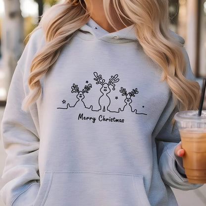 May include: A light blue hooded sweatshirt featuring a black line art graphic of three reindeer with antlers and small stars. The text Merry Christmas is printed in black script below the reindeer figures. The garment has a front kangaroo pocket.