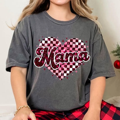 May include: A gray t-shirt with a pink and white checkered heart design. The word "Mama" is written in a pink glittery font inside the heart.