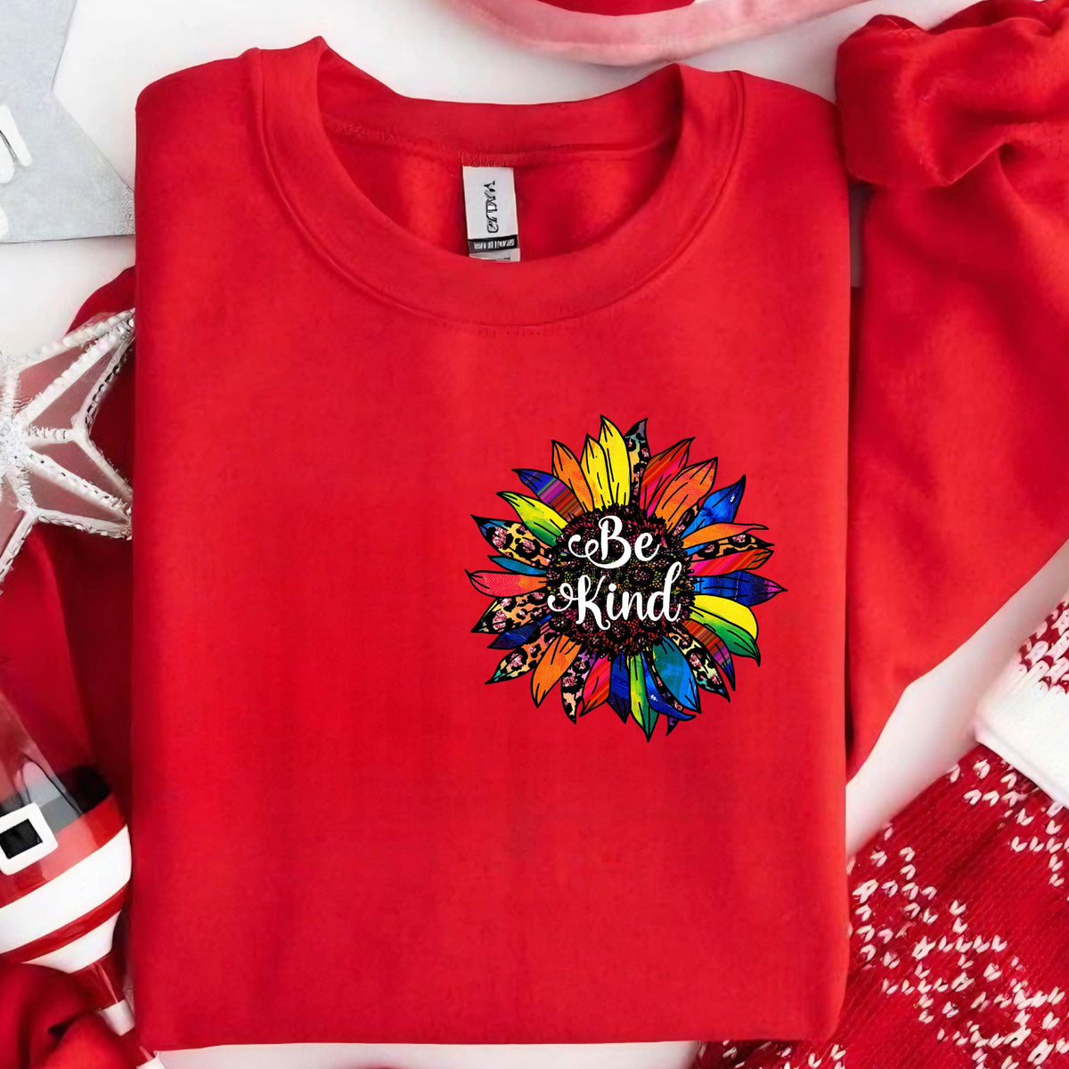 May include: Red sweatshirt with a colorful sunflower graphic and the text "Be Kind" in black.