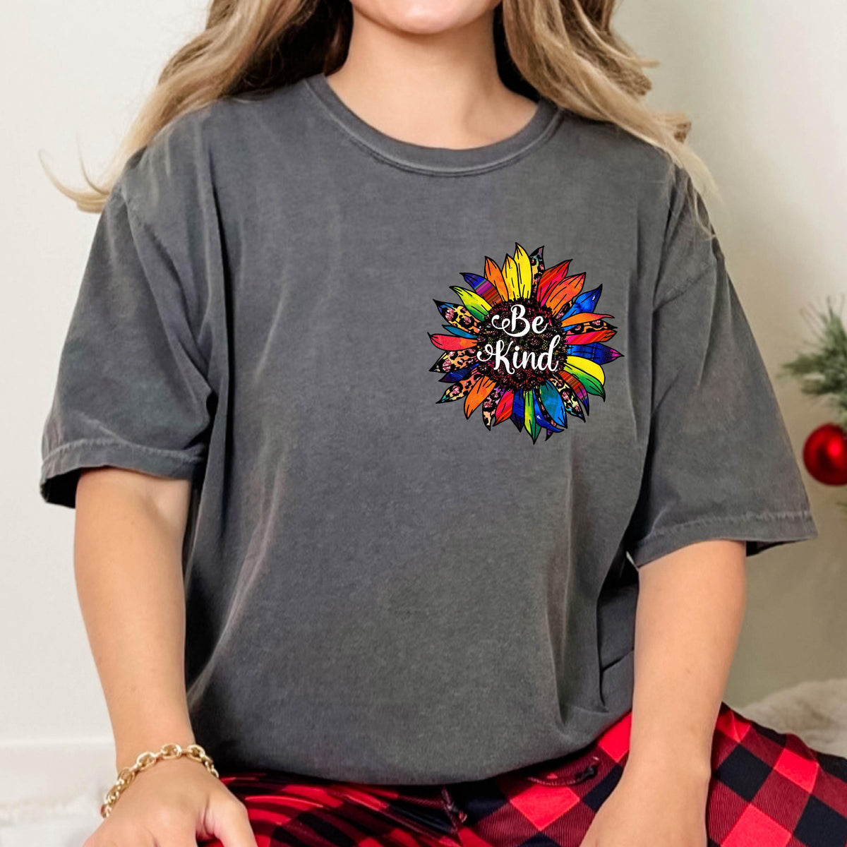 May include: A charcoal gray t-shirt featuring a colorful sunflower design. The sunflower has rainbow-colored petals and a leopard print center, with the words "Be Kind" in the center.