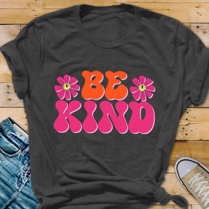 May include: A dark grey t-shirt with a pink and orange graphic that says "BE KIND" with two pink flowers with yellow smiley faces on them.