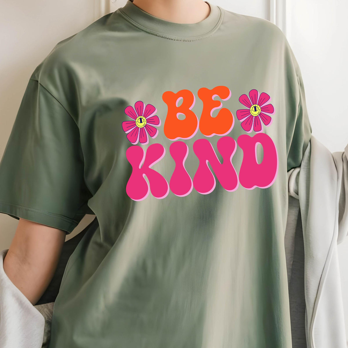May include: A green t-shirt with a pink and orange graphic that says "BE KIND" with two pink flowers with yellow smiley faces.