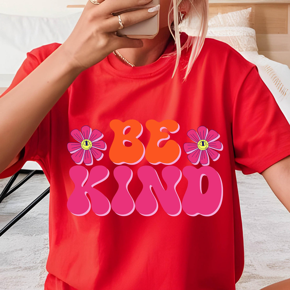 May include: Red t-shirt with a graphic print of the words "BE KIND" in pink, orange, and yellow with two pink flowers with yellow centers.