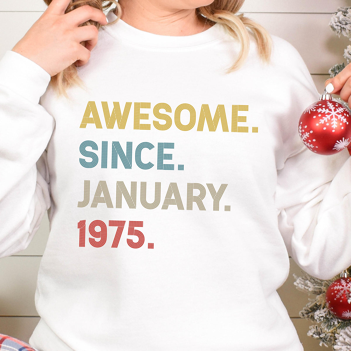 May include: White sweatshirt with the text "AWESOME. SINCE. JANUARY. 1975." in yellow, teal, tan, and red. The sweatshirt is a crew neck style.