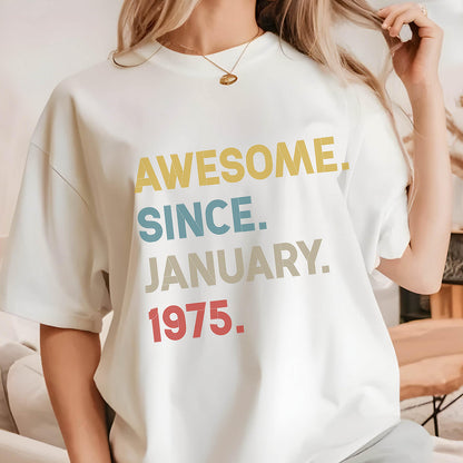 May include: A white short-sleeved t-shirt featuring the text AWESOME. SINCE. JANUARY. 1975. printed in a stacked design. The words are rendered in a striped font with yellow for AWESOME, blue for SINCE, beige for JANUARY, and red for 1975.