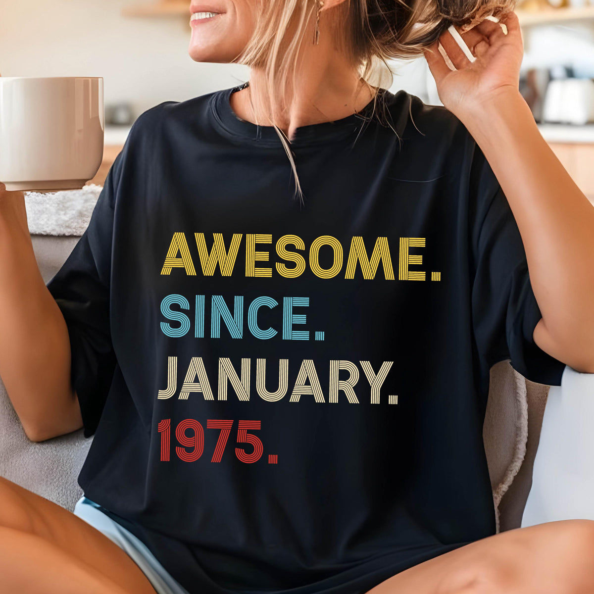 May include: A black crew neck t-shirt featuring the text AWESOME. SINCE. JANUARY. 1975. printed in a stacked, multi-colored striped font. The word AWESOME is yellow, SINCE is light blue, JANUARY is white, and 1975 is red, all in a bold sans-serif style.