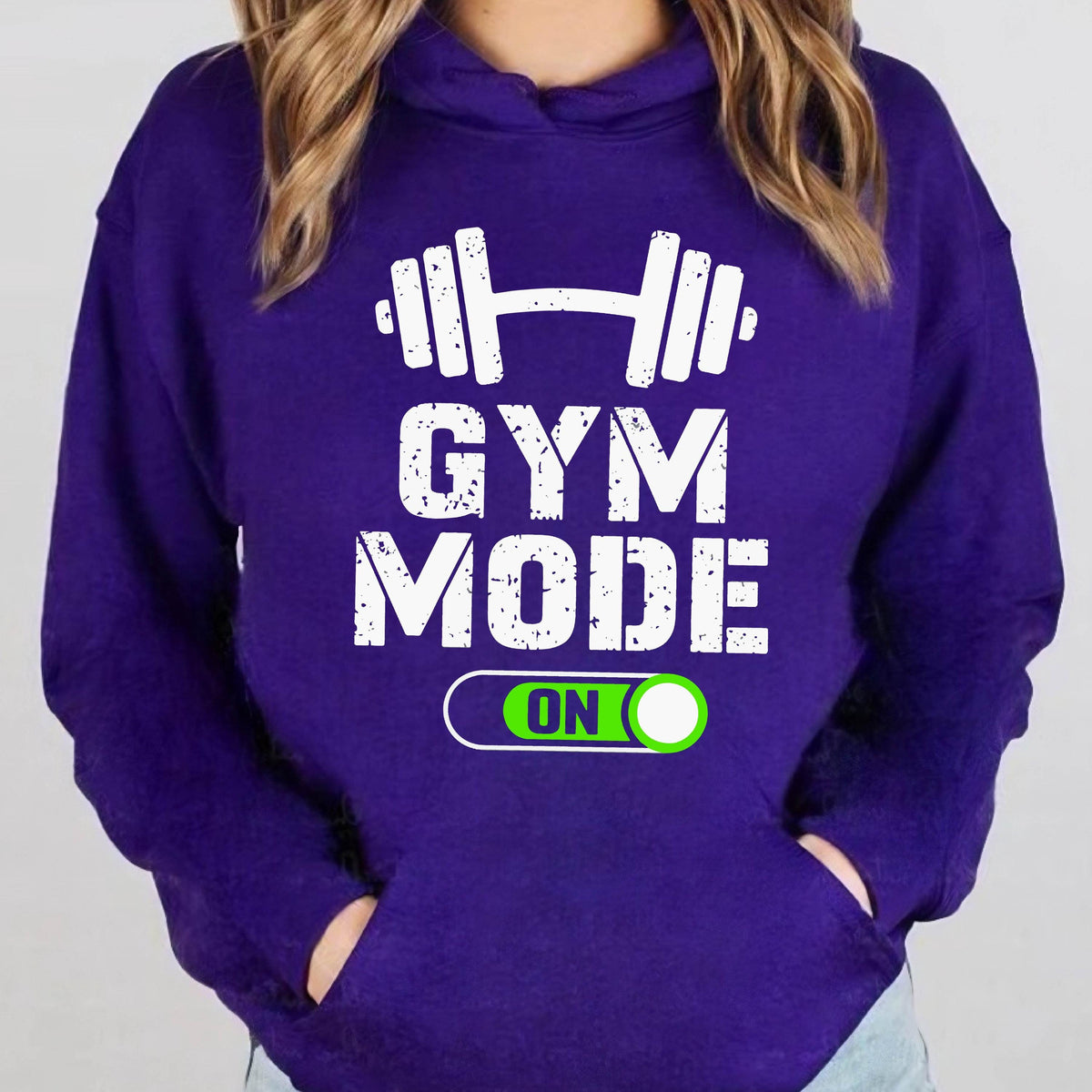 May include: A deep purple hooded sweatshirt featuring a white graphic of a barbell above the distressed white text GYM MODE. Below the text is a green and white toggle switch graphic with the word ON inside a rounded rectangular border.