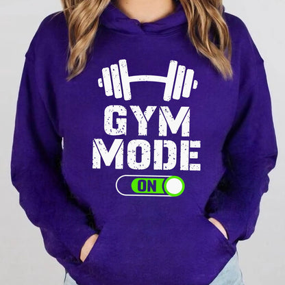 May include: A deep purple hooded sweatshirt featuring a white graphic of a barbell above the distressed white text GYM MODE. Below the text is a green and white toggle switch graphic with the word ON inside a rounded rectangular border.