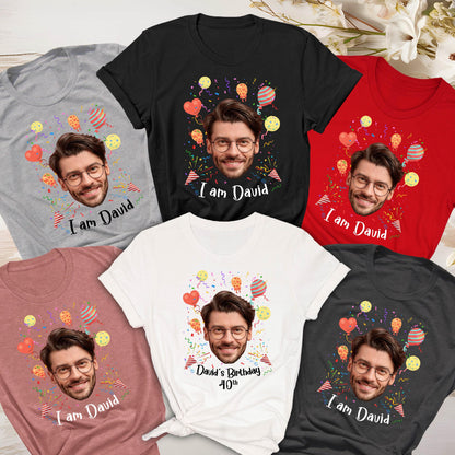 May include: A collection of five short-sleeved t-shirts in gray, black, red, dusty rose, and white. Each shirt features a printed graphic of a man's face, colorful balloons, confetti, and the text "I am David" or "David's Birthday 40th".