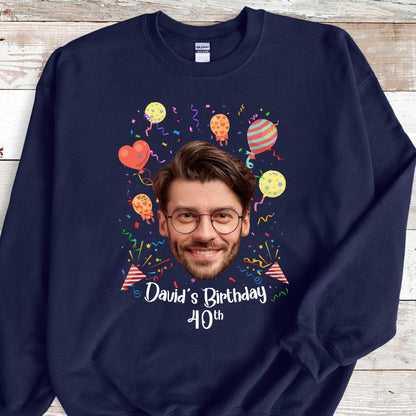 May include: A navy blue sweatshirt with a personalized design featuring a man's face surrounded by colorful balloons and confetti. The text "David's Birthday 40th" is printed below the face.