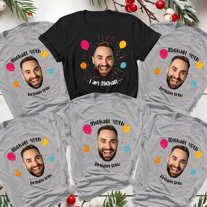 May include: A collection of five t-shirts, one black and four heather gray, each featuring a printed photograph of a man's face surrounded by colorful balloons and confetti. The gray shirts read "Michael 40th Birthday Crew" and the black shirt reads "I am Michael".