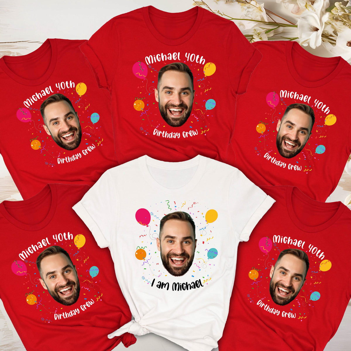 May include: A collection of five short-sleeved t-shirts, four in red and one in white. Each shirt features a central graphic of a man's face surrounded by colorful balloons, confetti, and the text Michael 40th Birthday Crew or I am Michael.