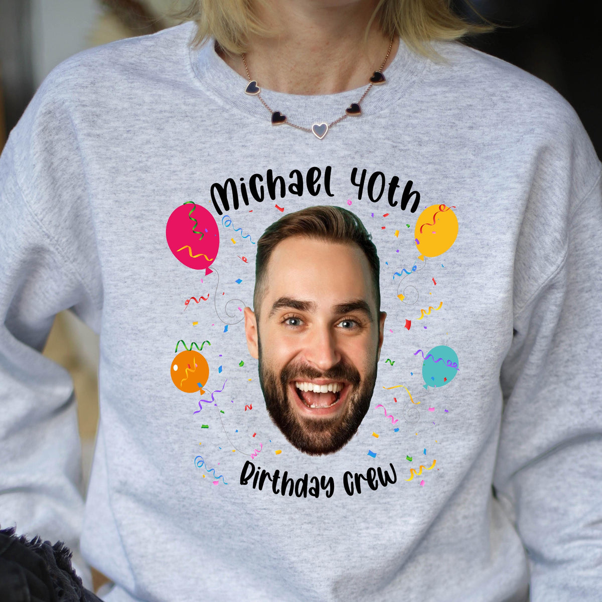 May include: A gray sweatshirt with a birthday theme. It features a man's face with the text "Michael 40th Birthday Crew" and colorful balloons.