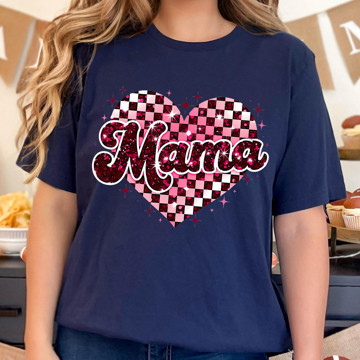 May include: A navy blue t-shirt with a pink and white checkered heart design. The word "Mama" is written in a pink glittery font inside the heart.