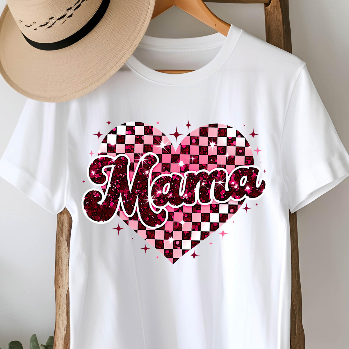 May include: White t-shirt with a pink and white checkered heart design and the word "Mama" in a pink glittery font.