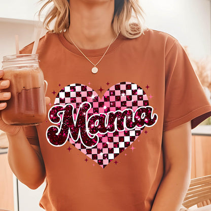 May include: A brown t-shirt with a pink and white checkered heart design and the word "Mama" in a glittery pink font.