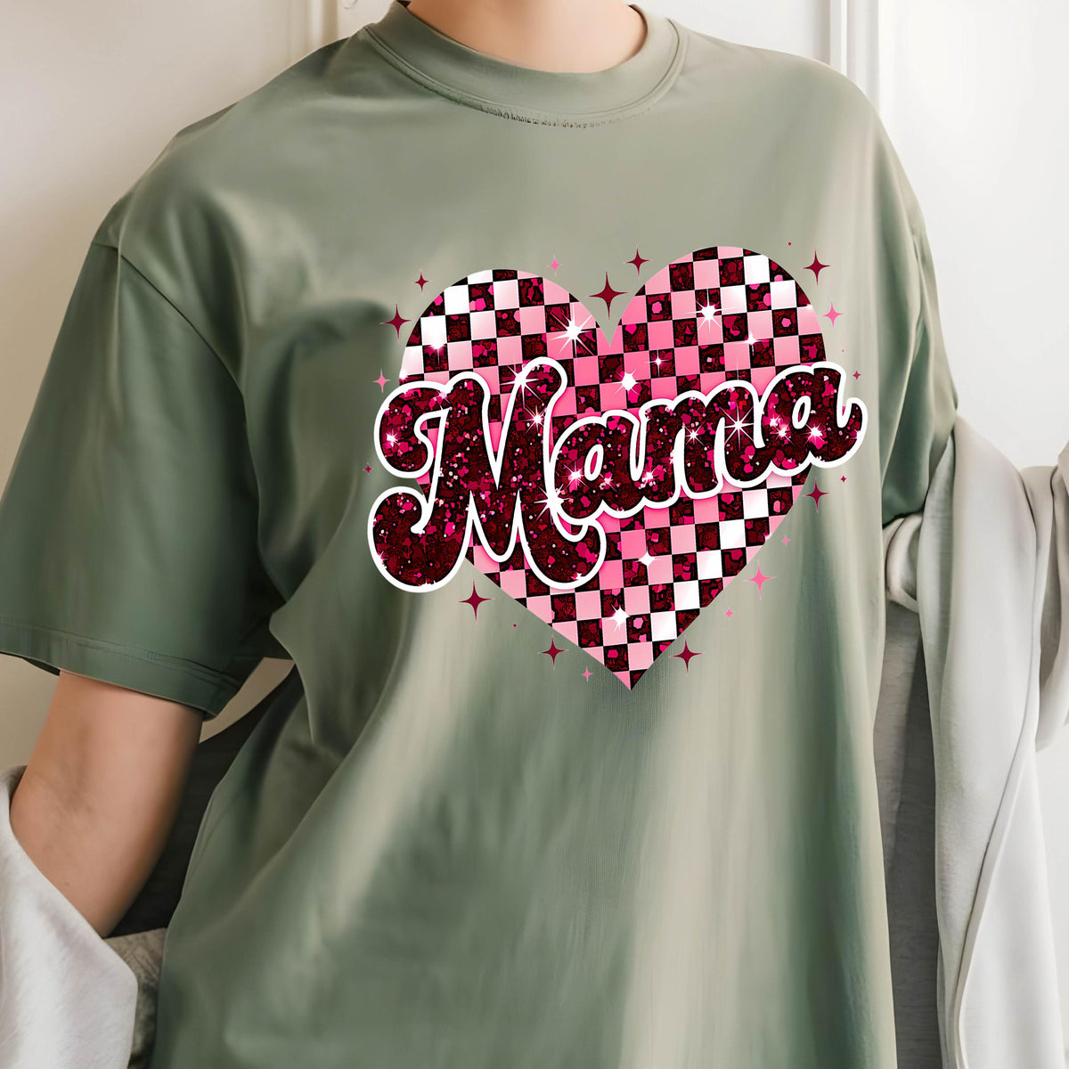 May include: A green t-shirt with a pink and white checkered heart with the word "Mama" in pink glitter letters.