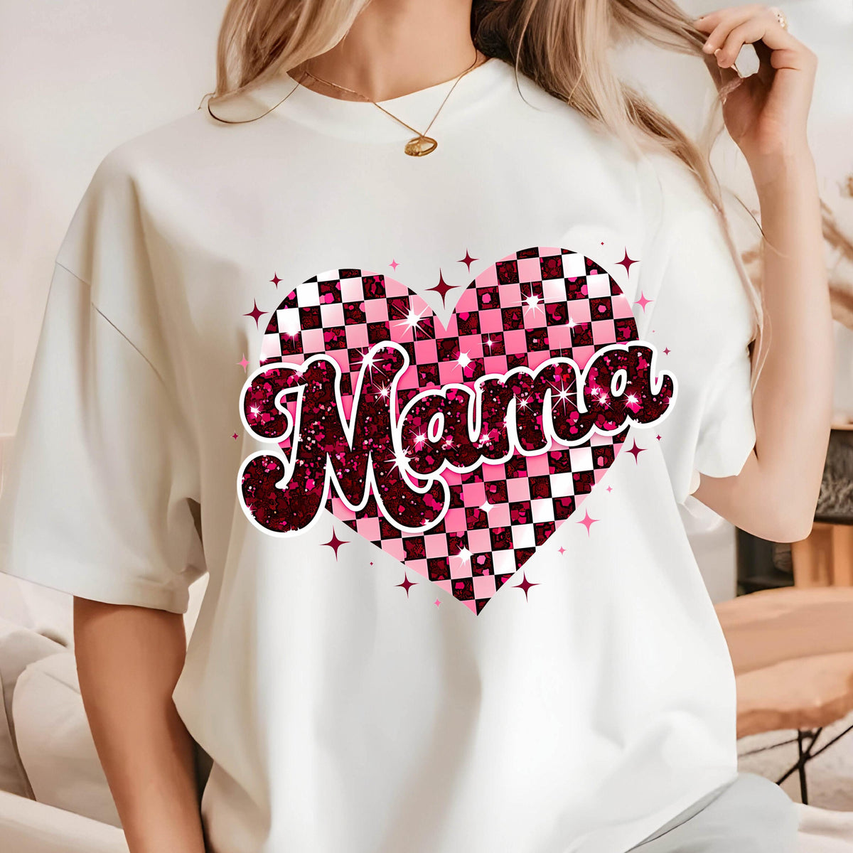 May include: White t-shirt with a pink and black checkered heart design and the word "Mama" in pink glitter letters.