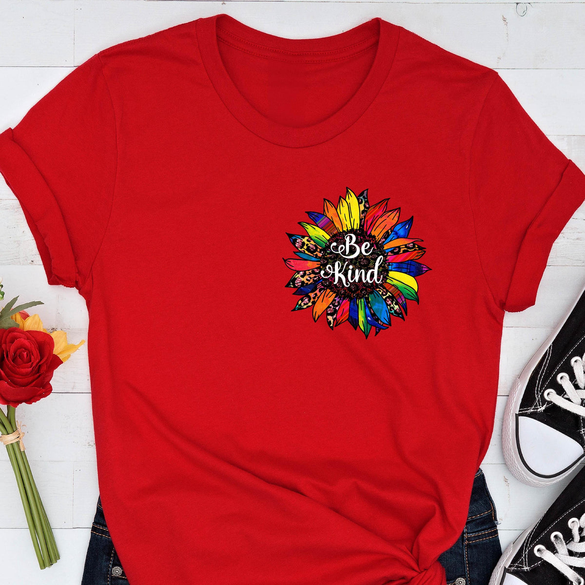 May include: Red t-shirt with a rainbow sunflower graphic and the text "Be Kind" printed on it.