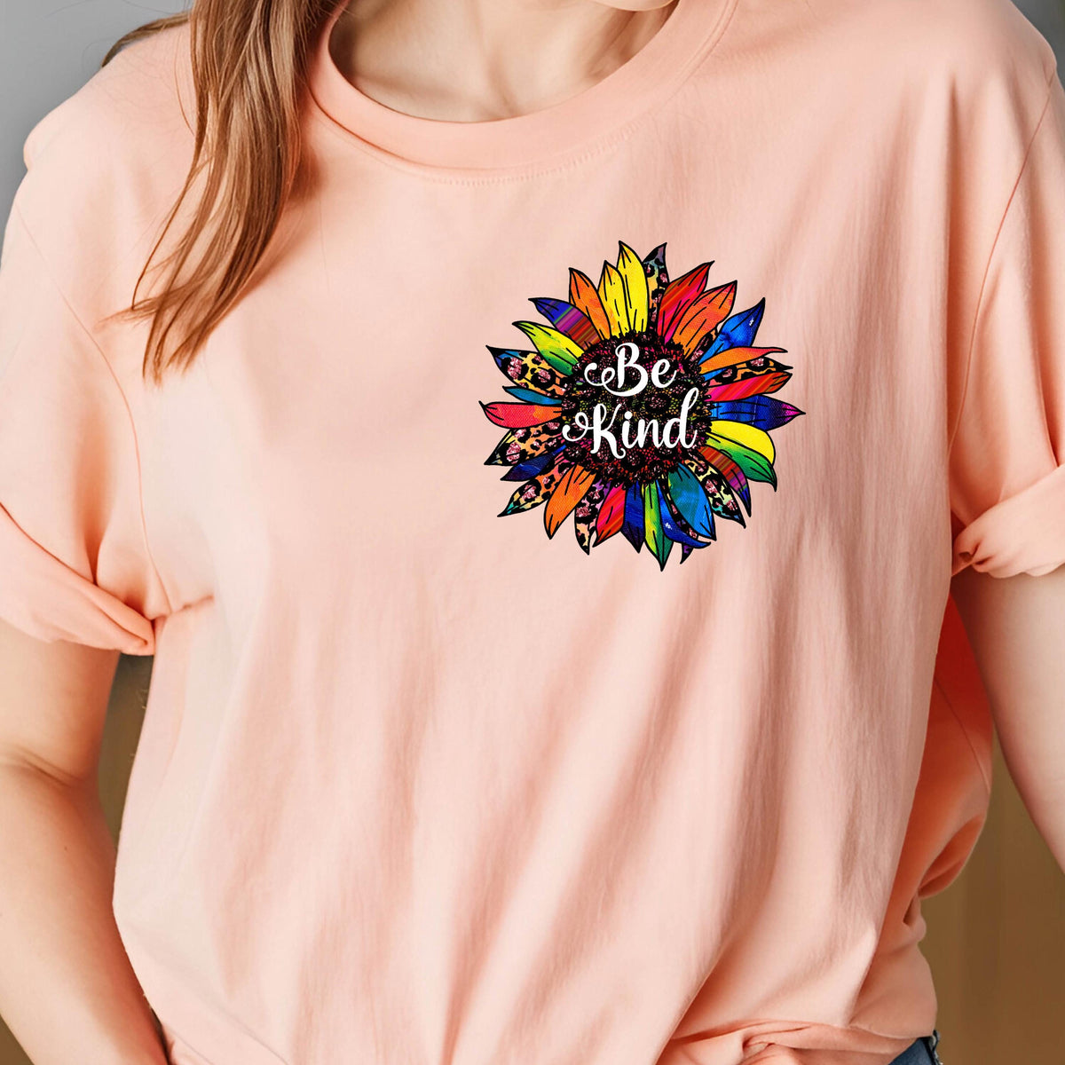 May include: A pink t-shirt with a colorful sunflower graphic and the text "Be Kind" in the center.
