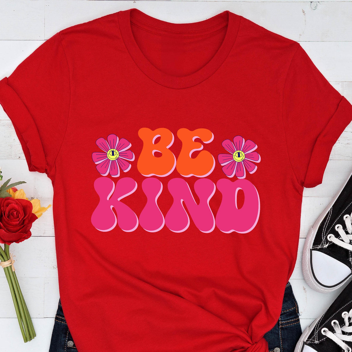 May include: Red t-shirt with a retro-style graphic that says "Be Kind" in pink and orange letters with two pink flowers on either side of the text.