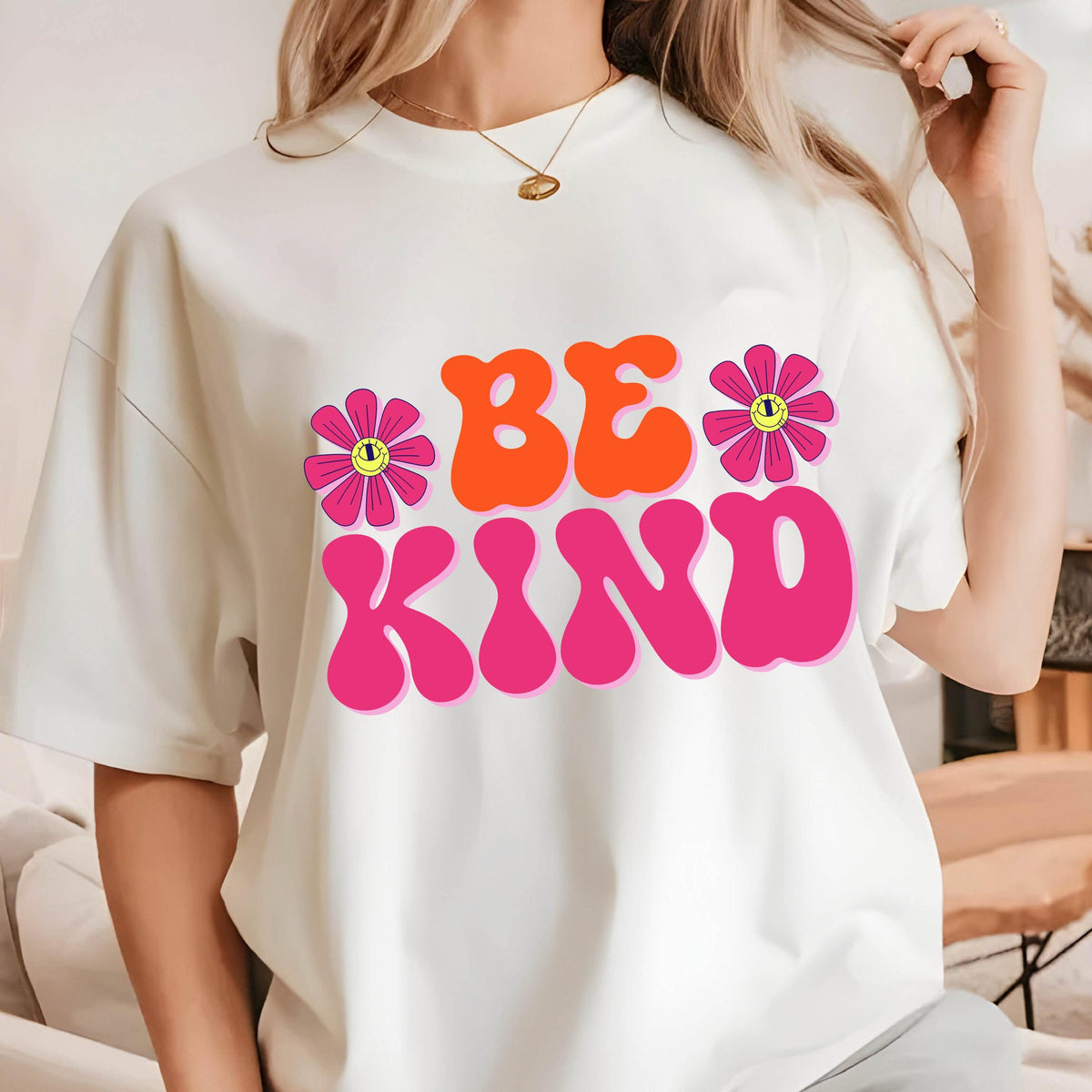 May include: White t-shirt with a pink and orange graphic that says "Be Kind" with two pink flowers with yellow smiley faces.