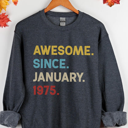 May include: A dark gray sweatshirt with the text "AWESOME. SINCE. JANUARY. 1975." in yellow, blue, and red. The sweatshirt is hanging on a wooden hanger.