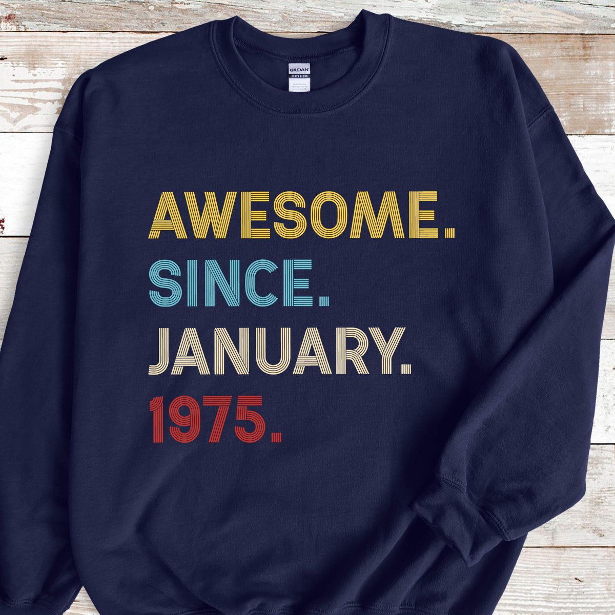 May include: Navy blue sweatshirt with the text "AWESOME. SINCE. JANUARY. 1975." in yellow, blue, beige, and red. The sweatshirt has a crew neck and long sleeves.