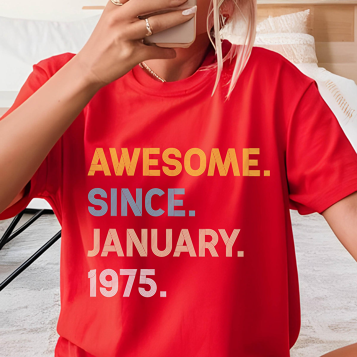 May include: A bright red short-sleeved t-shirt featuring the text "AWESOME. SINCE. JANUARY. 1975." printed on the front. The word "AWESOME." is in yellow, "SINCE." is in blue, and "JANUARY. 1975." is in white, all with a striped line effect.