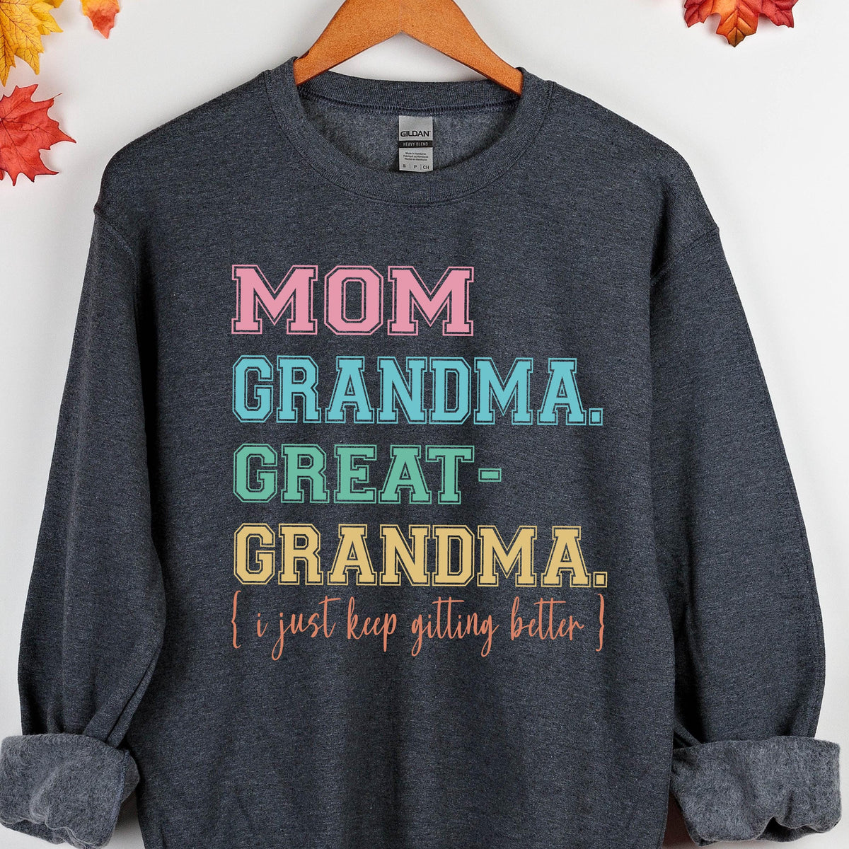 May include: A dark gray sweatshirt with the text "MOM GRANDMA. GREAT-GRANDMA. (I just keep getting better)" printed in rainbow colors.