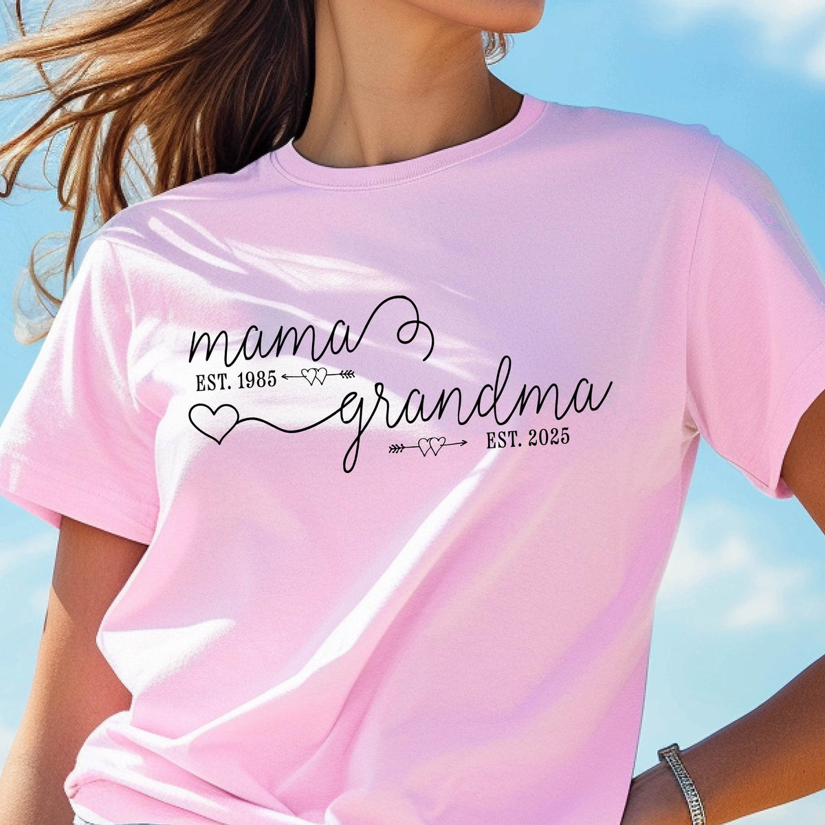 May include: Pink t-shirt with the text "mama est. 1985 grandma est. 2025" with a heart and arrow design.