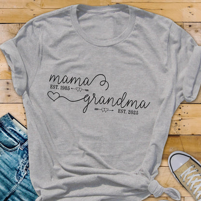 May include: Gray t-shirt with the text "mama est. 1985" and "grandma est. 2025" with hearts and arrows between the words.