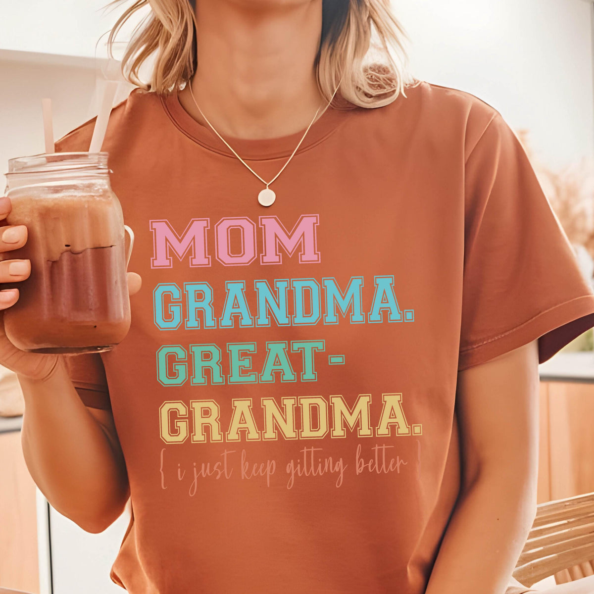 May include: A brown t-shirt with the text "MOM GRANDMA. GREAT-GRANDMA. (I just keep getting better)" printed in colorful letters.