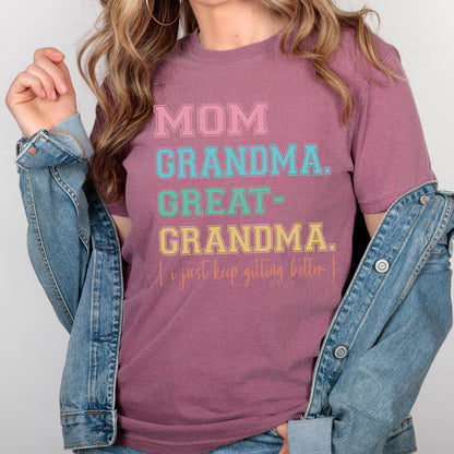 May include: A mauve t-shirt with the text "MOM GRANDMA. GREAT-GRANDMA. I just keep getting better." in colorful block letters.