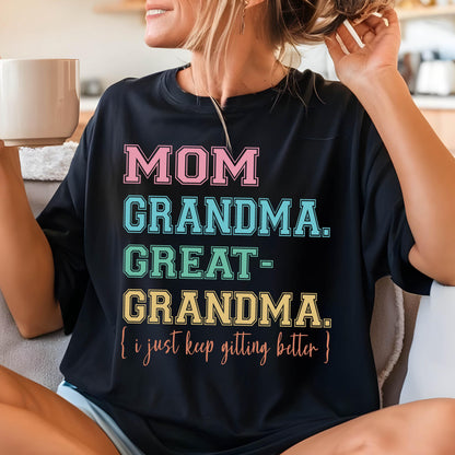 May include: Black t-shirt with a colorful graphic that reads "MOM GRANDMA GREAT-GRANDMA. (I just keep getting better!)"