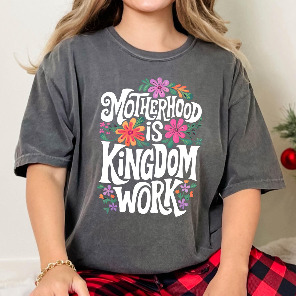 May include: A gray t-shirt with a white graphic that says "Motherhood is Kingdom Work" surrounded by colorful flowers.