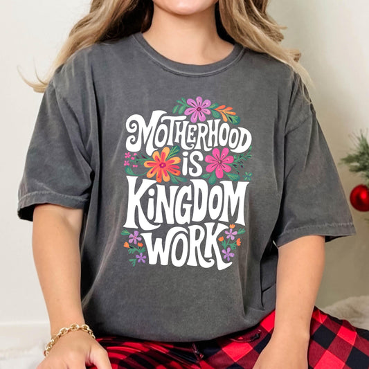 May include: A gray t-shirt with a white graphic that says "Motherhood is Kingdom Work" surrounded by colorful flowers.