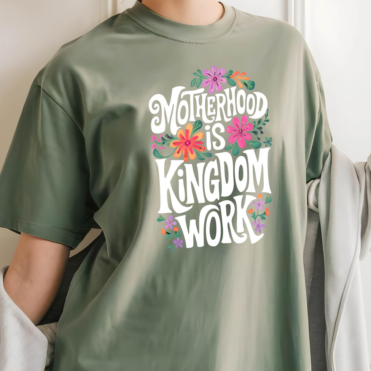 May include: A green t-shirt with a white graphic that says "Motherhood is Kingdom Work" surrounded by colorful flowers.