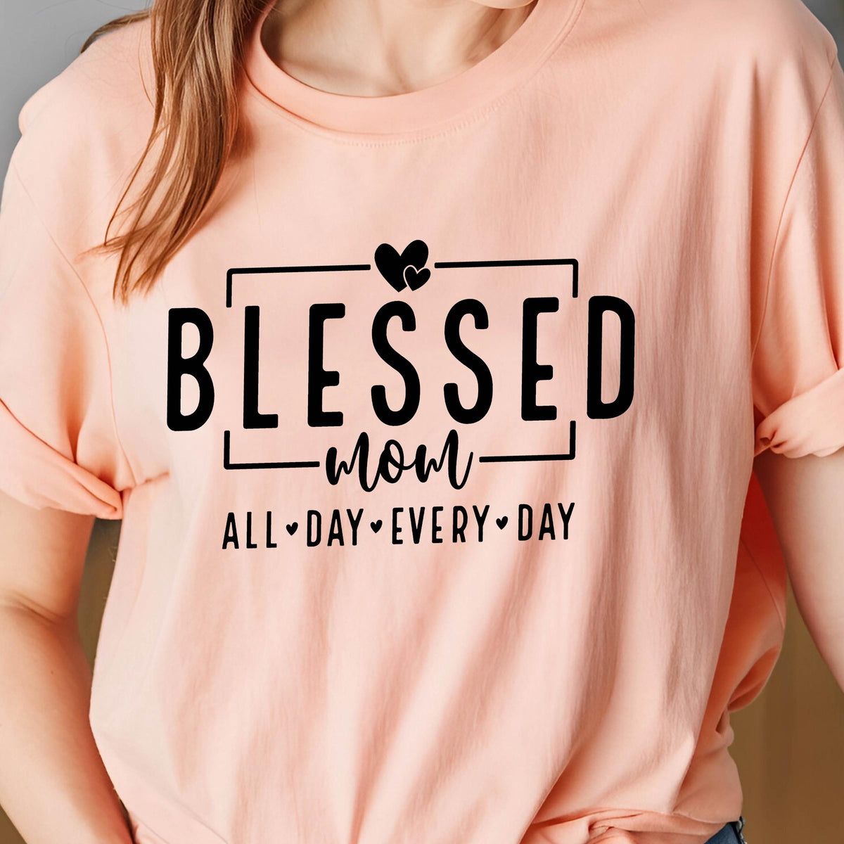 May include: A pink t-shirt with black text that reads "Blessed Mom All Day Every Day" with a heart symbol between each word.