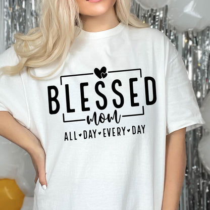 May include: White t-shirt with black text that reads "Blessed Mom All Day Every Day" with a heart symbol between each word.