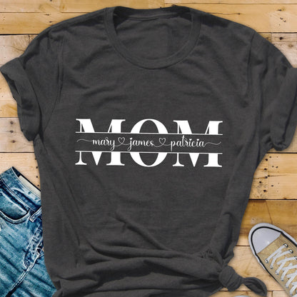 May include: Gray t-shirt with the word "MOM" in white text. Below the word "MOM" is a line with the names "mary", "james", and "patricia" separated by hearts.