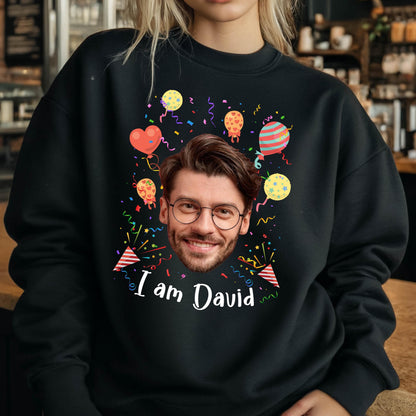May include: Black sweatshirt with a colorful birthday design featuring a person's face, balloons, and confetti. The text "I am David" is printed on the front.