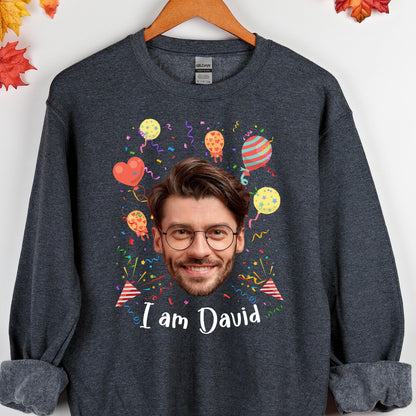 May include: A dark gray sweatshirt with a personalized design featuring a face surrounded by colorful balloons and confetti. The text "I am David" is printed below the face.