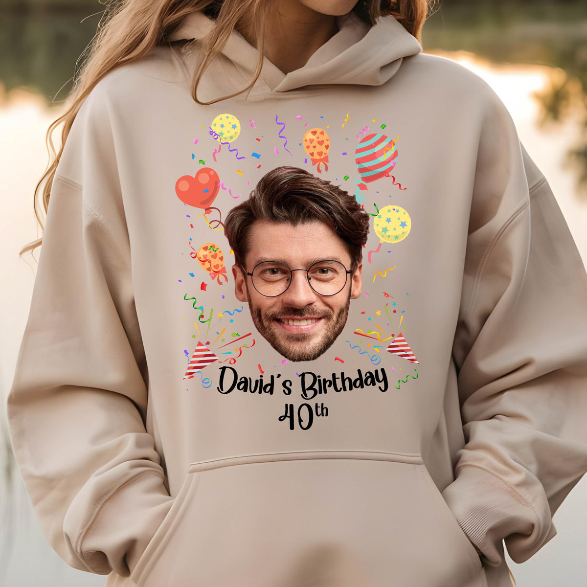 May include: A beige hoodie with a personalized birthday design. The design features a person's face, colorful balloons, confetti, and the text "David's Birthday 40th".