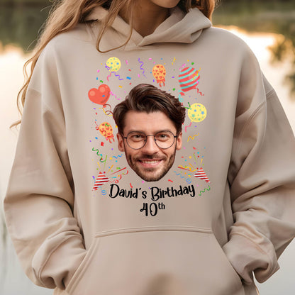 May include: A beige hoodie with a personalized birthday design. The design features a person's face, colorful balloons, confetti, and the text "David's Birthday 40th".