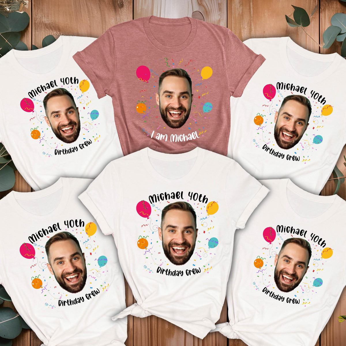 May include: Five t-shirts featuring a printed graphic of a man's face surrounded by colorful balloons and confetti. Four shirts are white with the text Michael 40th Birthday Crew, and one mauve shirt features the text I am Michael.