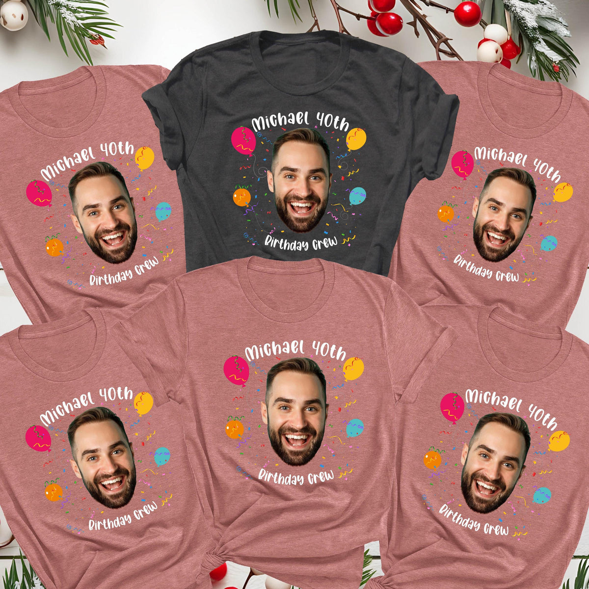 May include: Five short-sleeve t-shirts in heather mauve and charcoal gray. Each shirt features a central graphic of a man's face surrounded by colorful balloons and confetti, with the white text Michael 40th Birthday Crew printed above and below.