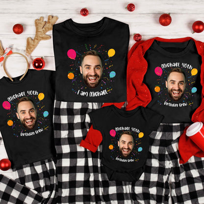 May include: A collection of black t-shirts and a baby bodysuit featuring a printed photograph of a smiling man, colorful balloons, confetti, and the text "Michael 40th" along with "I am Michael" or "Birthday Crew" in white lettering.